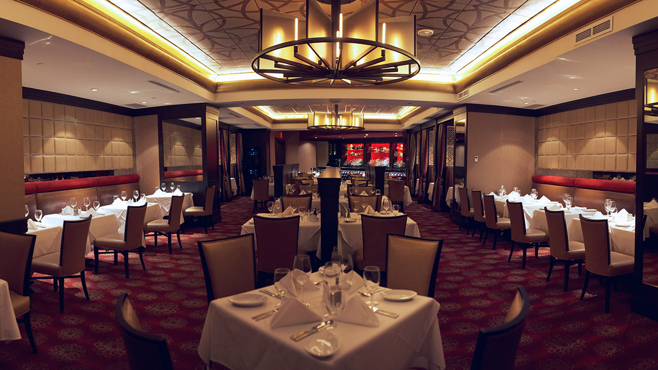 An elegant restaurant scene with tables and chairs meticulously set, creating a welcoming environment for dinner guests.